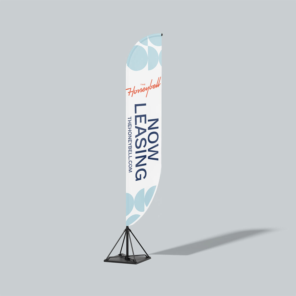 The Honeybell branded feather flag banner displaying Now Leasing message with apartment community logo and website in navy and light blue