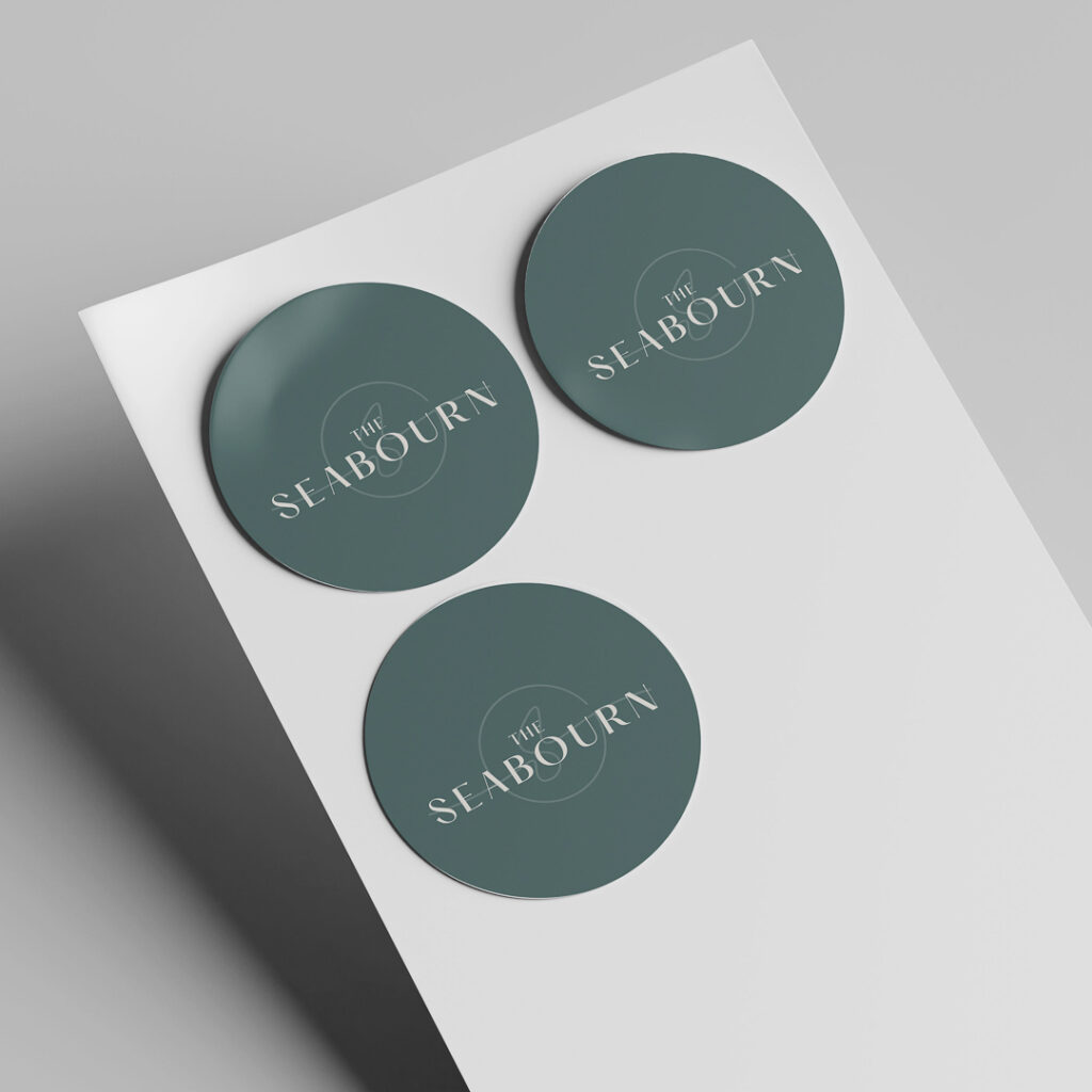 The Seabourn branded circular stickers in teal green with white logo showcasing apartment community brand consistency across small touchpoints