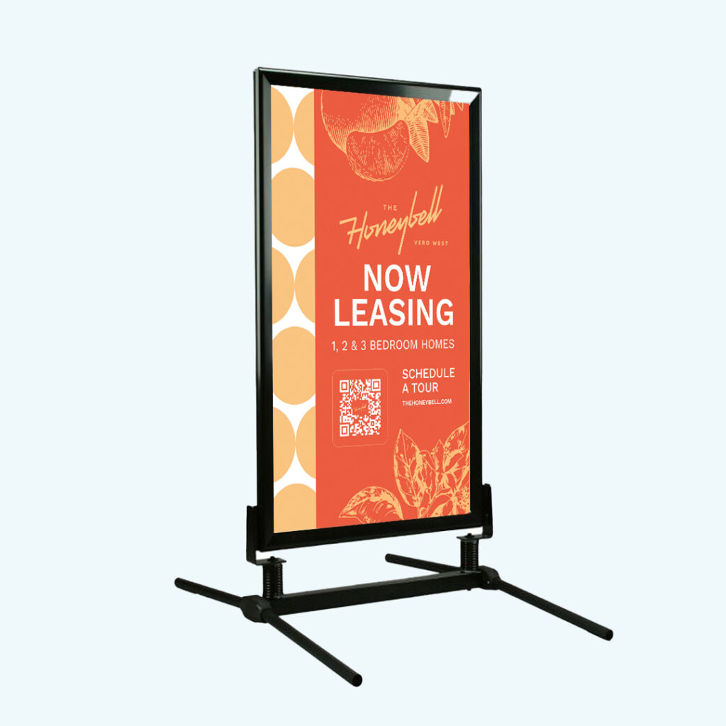 The Honeybell branded windmaster sidewalk sign featuring Now Leasing message with coral and navy color scheme and apartment community branding